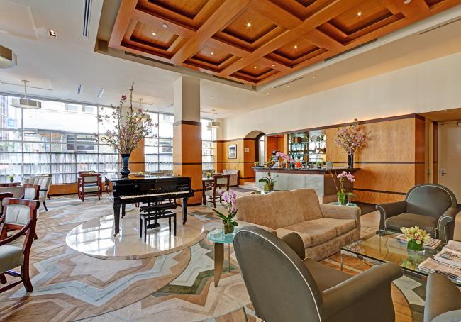 Grand Lobby with plenty of seating, tables, floor-to-ceiling windows, and a grand piano.