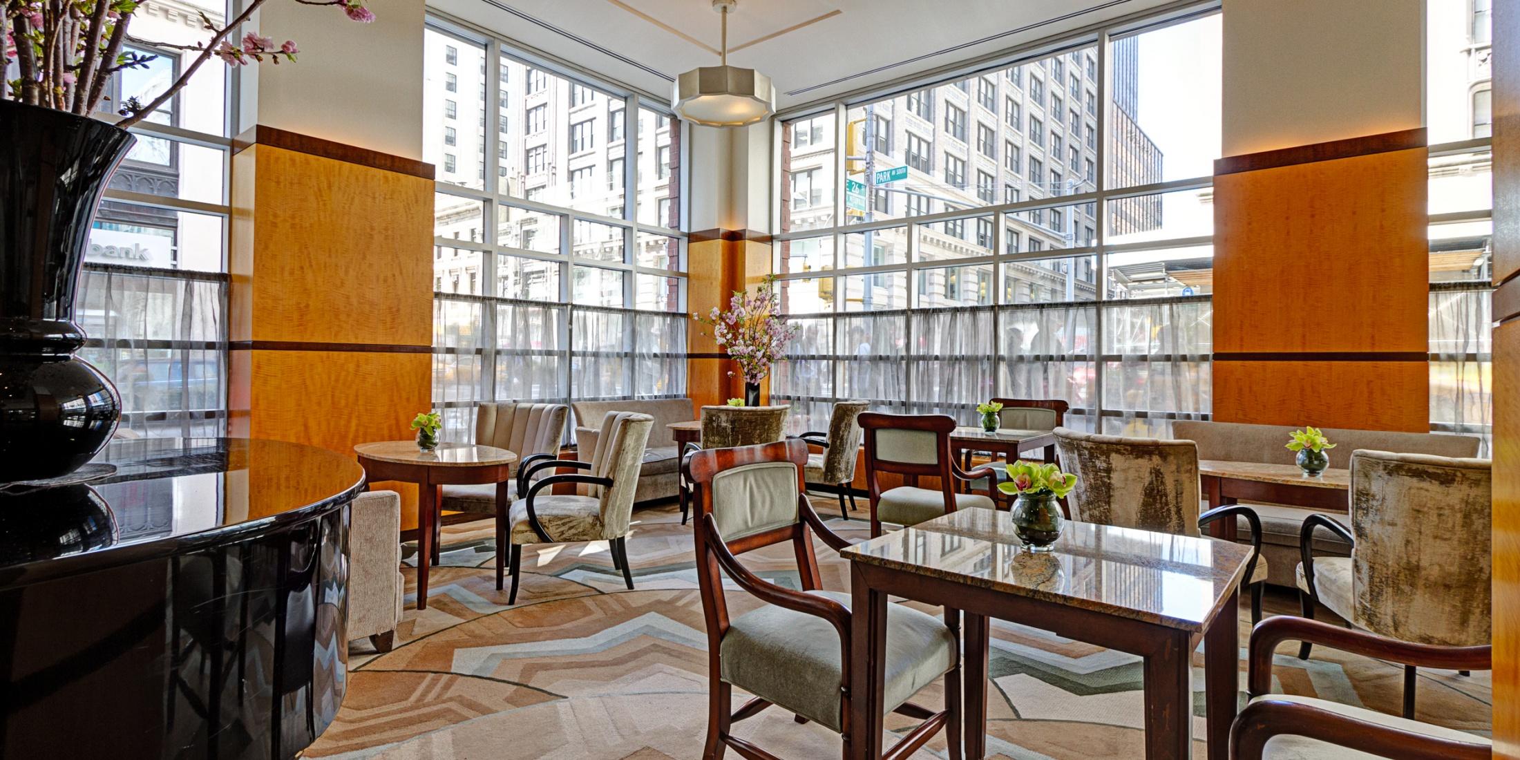 Grand Lobby with plenty of seating, tables, floor-to-ceiling windows, and a grand piano.