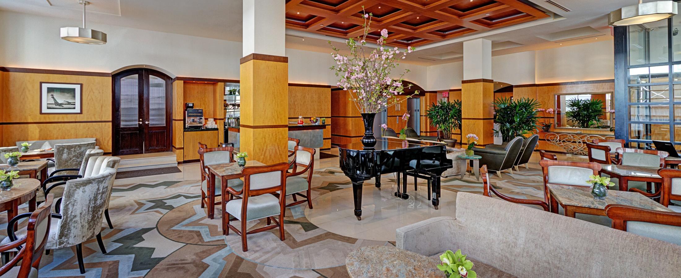 Grand Lobby with plenty of seating, tables, floor-to-ceiling windows, and a grand piano.